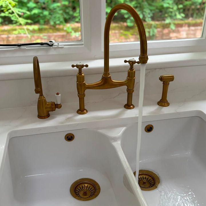 Brass bridge tap over a white ceramic double sink