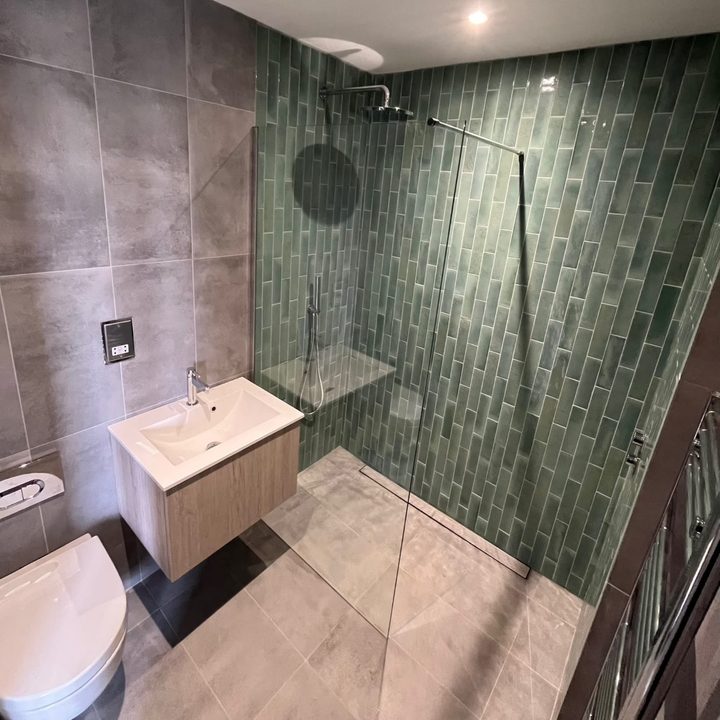 Wetroom with a walk-in shower and green metro tiling